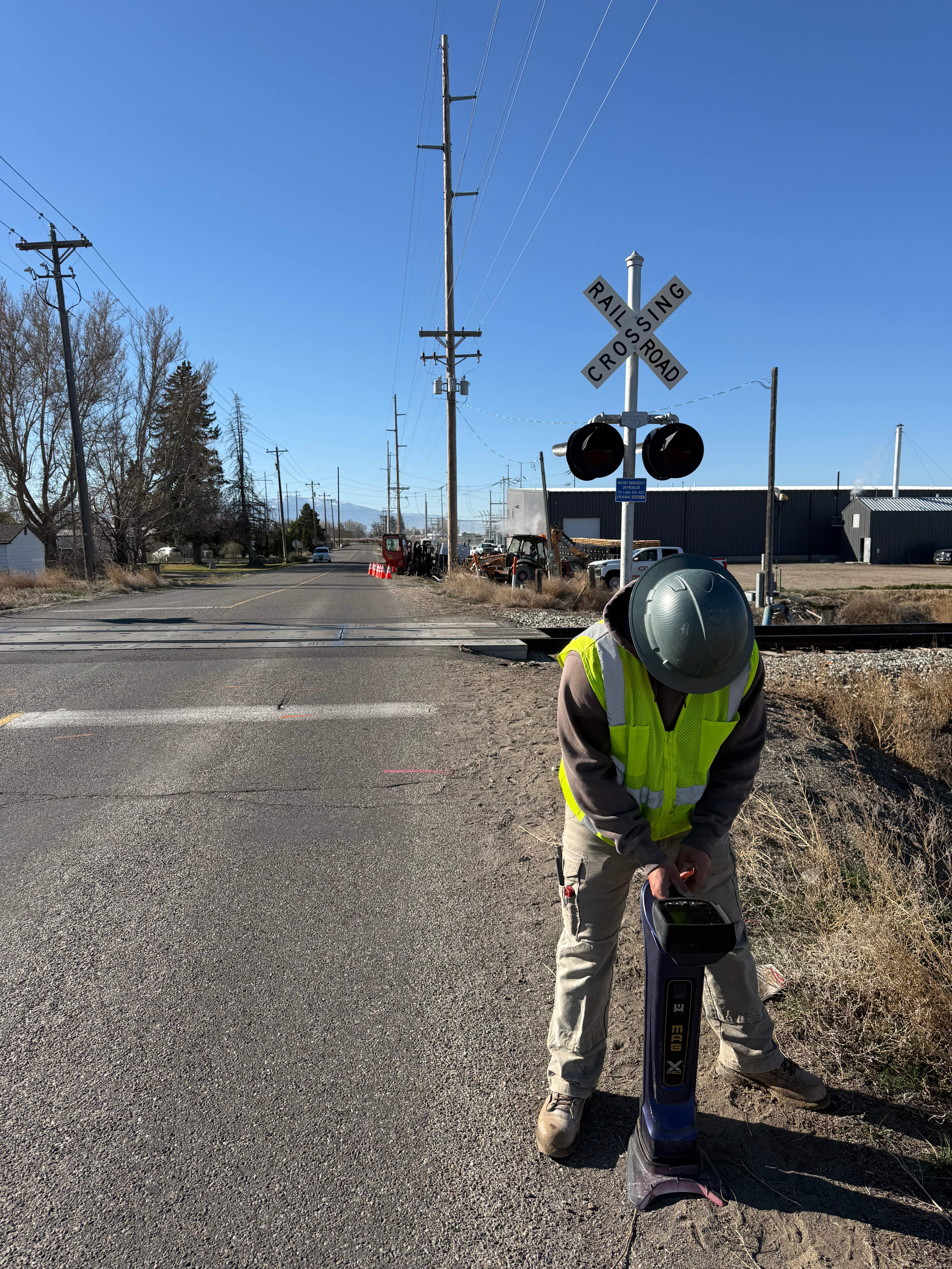 Utility locating technician using detection equipment at railroad crossing