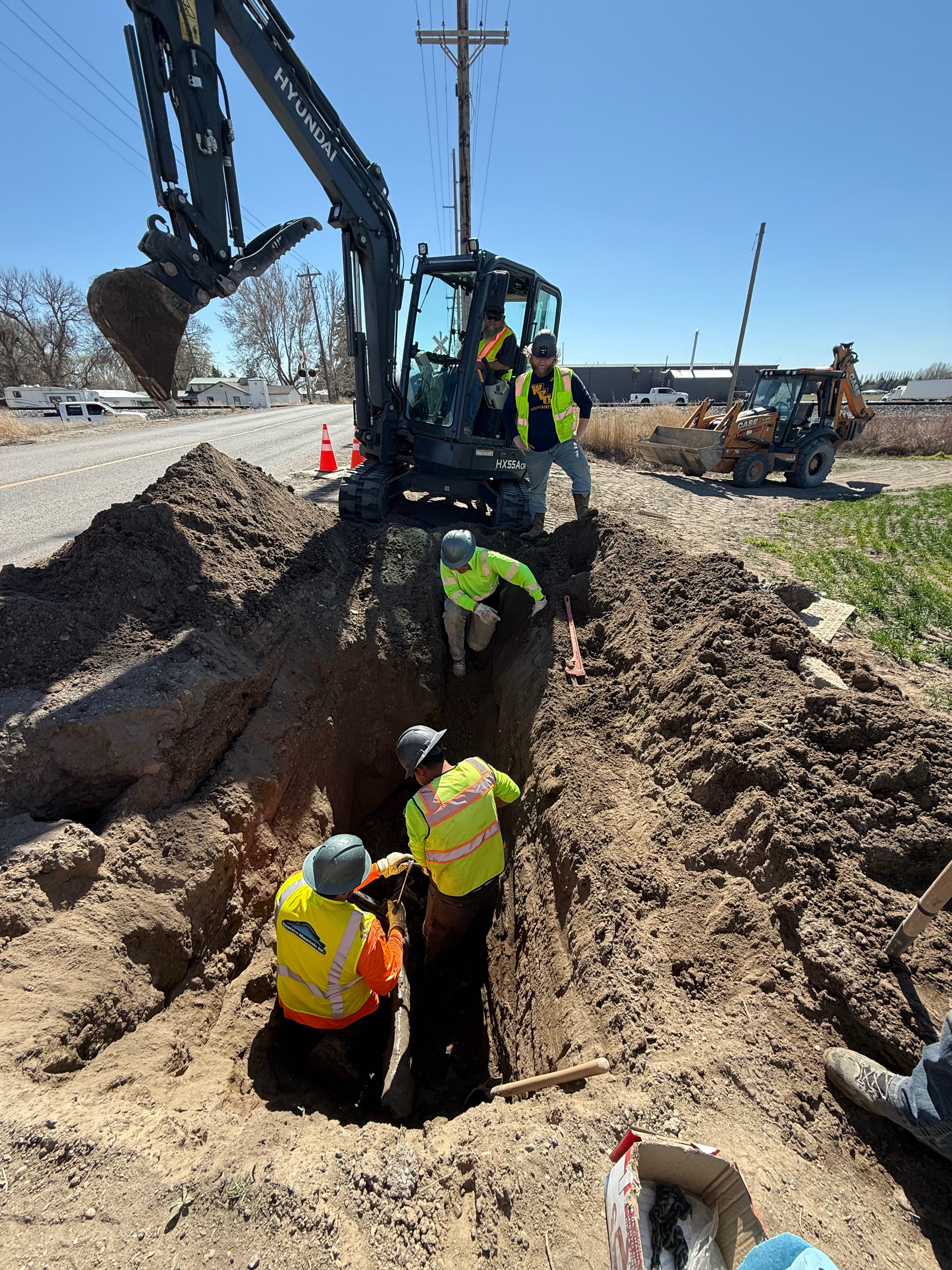 Power distribution crew excavating deep utility trench with Hyundai excavator